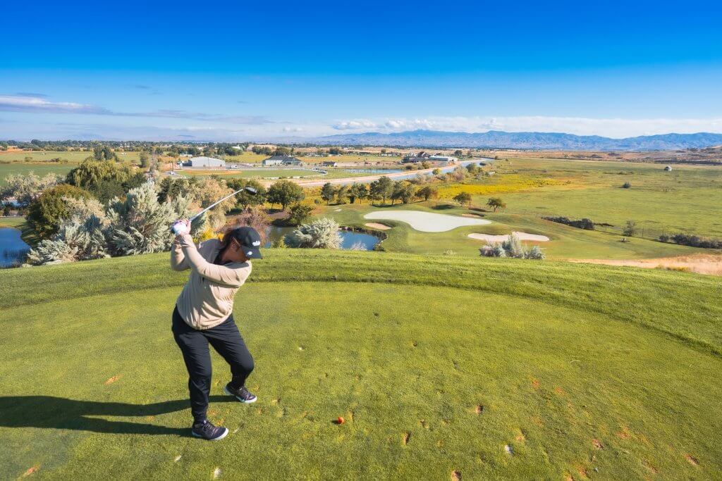 Woman tees off at Falcon Crest Golf Course. 