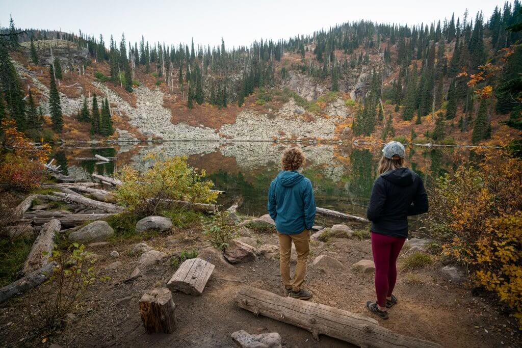 Two people stand at the waters edge at Caribou Lake near Sandpoint Idaho. 