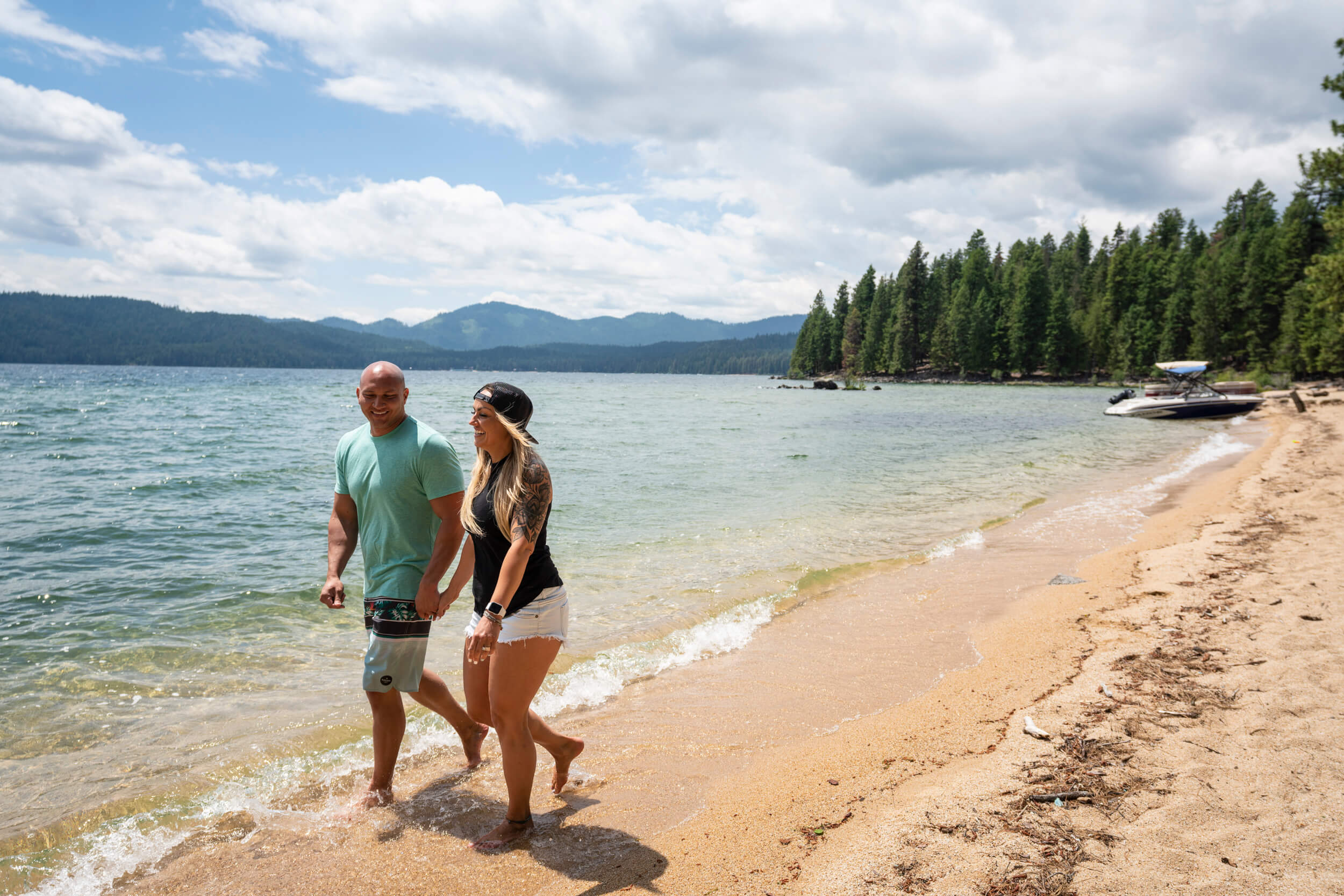 A couple holds hands and walks along the beach at Priest Lake.