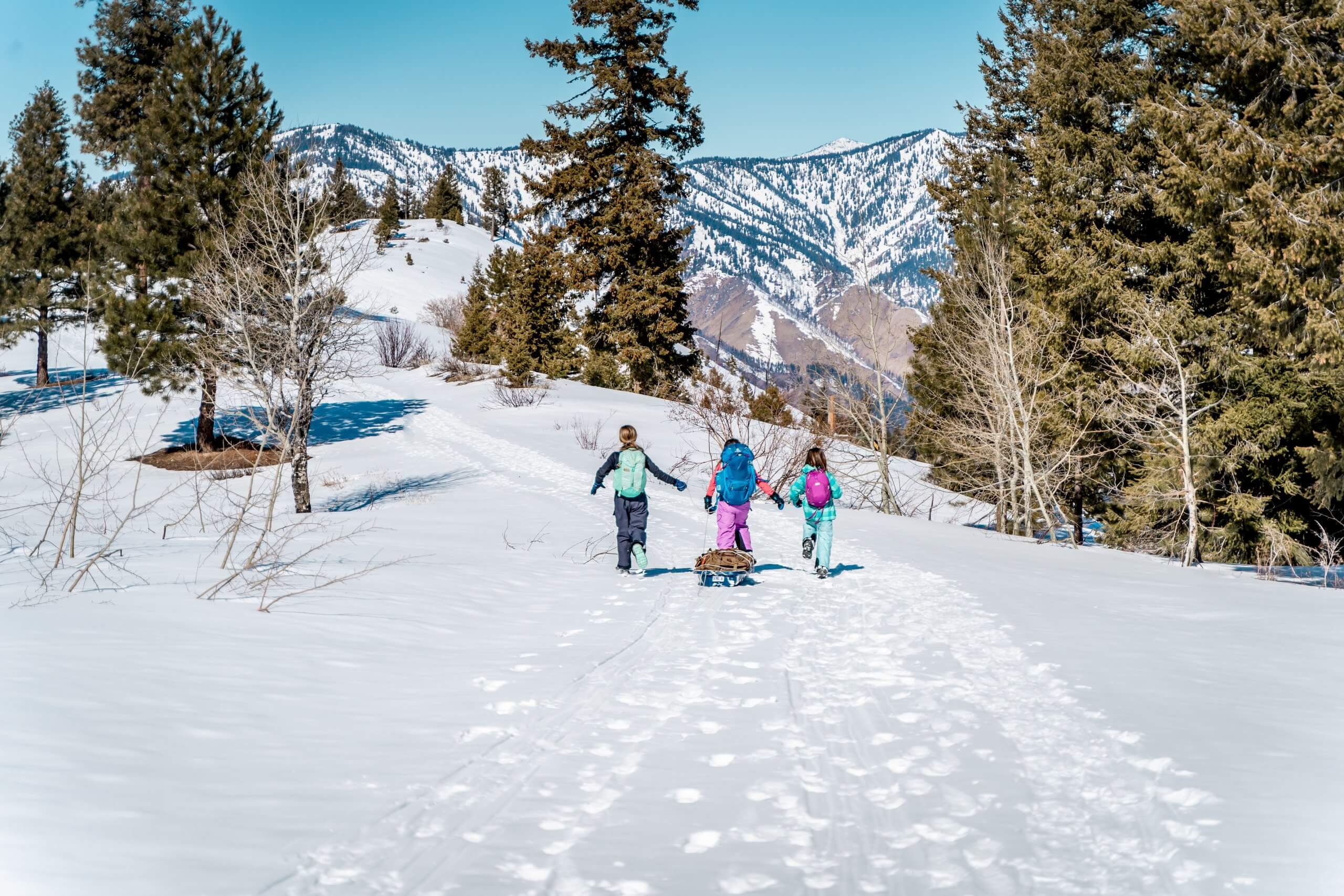 A group of kids hike to a yurt in the winter.