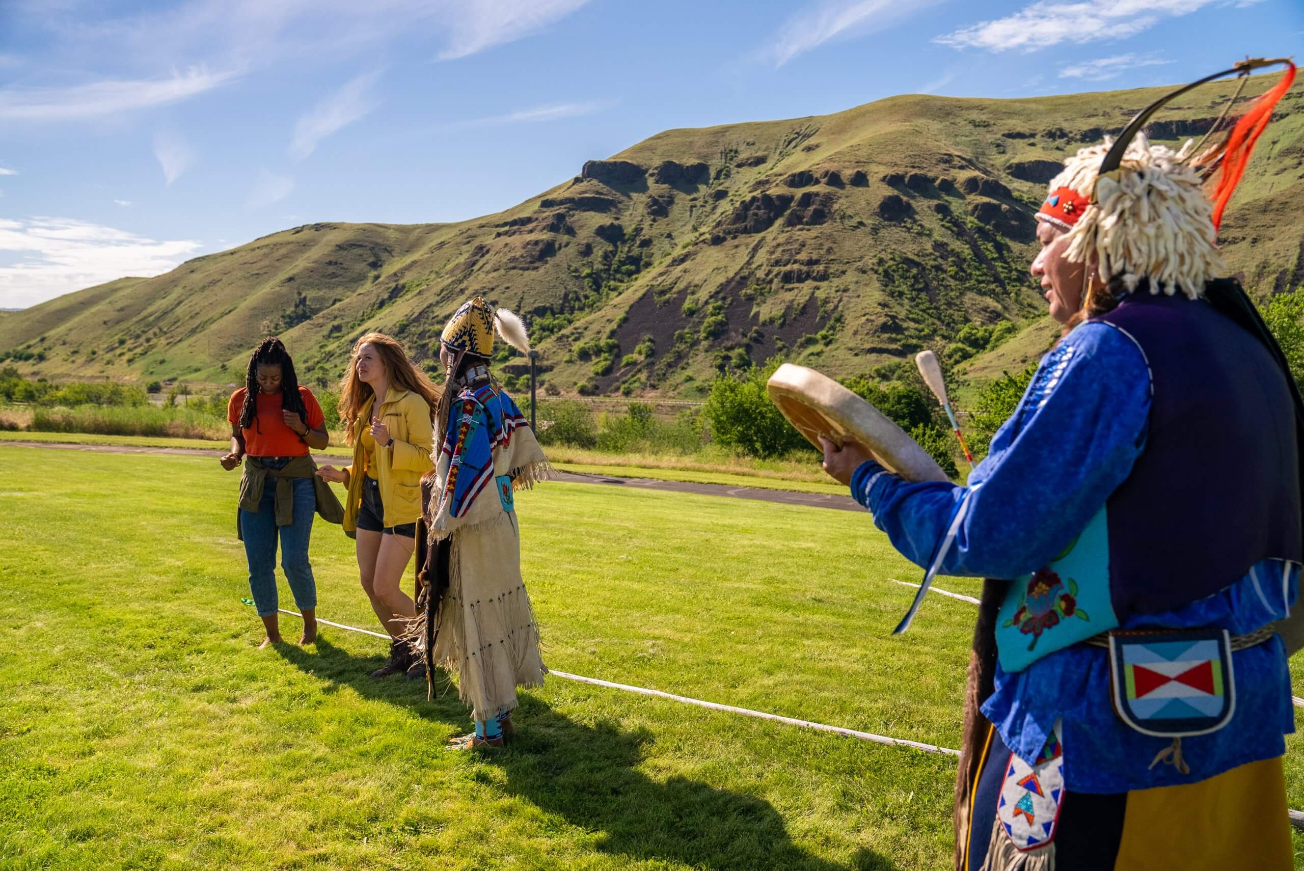 Two visitors enjoying drum music with two members of the Nez Perce tribe in Nez Perce National Historical Park.  