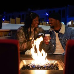 A couple sits around a fire at night enjoying a winter night.