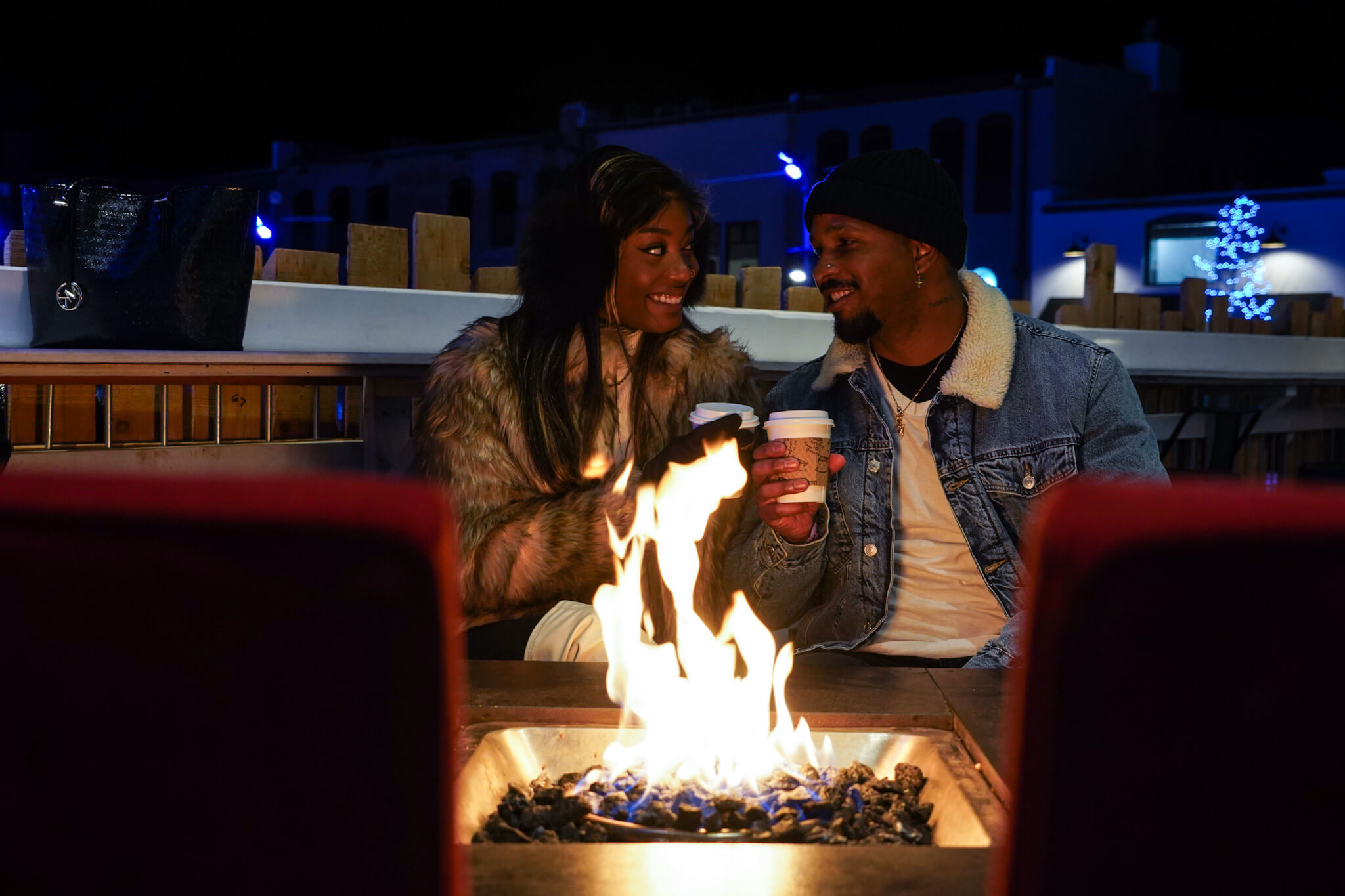 A couple sits around a fire at night enjoying a winter night.