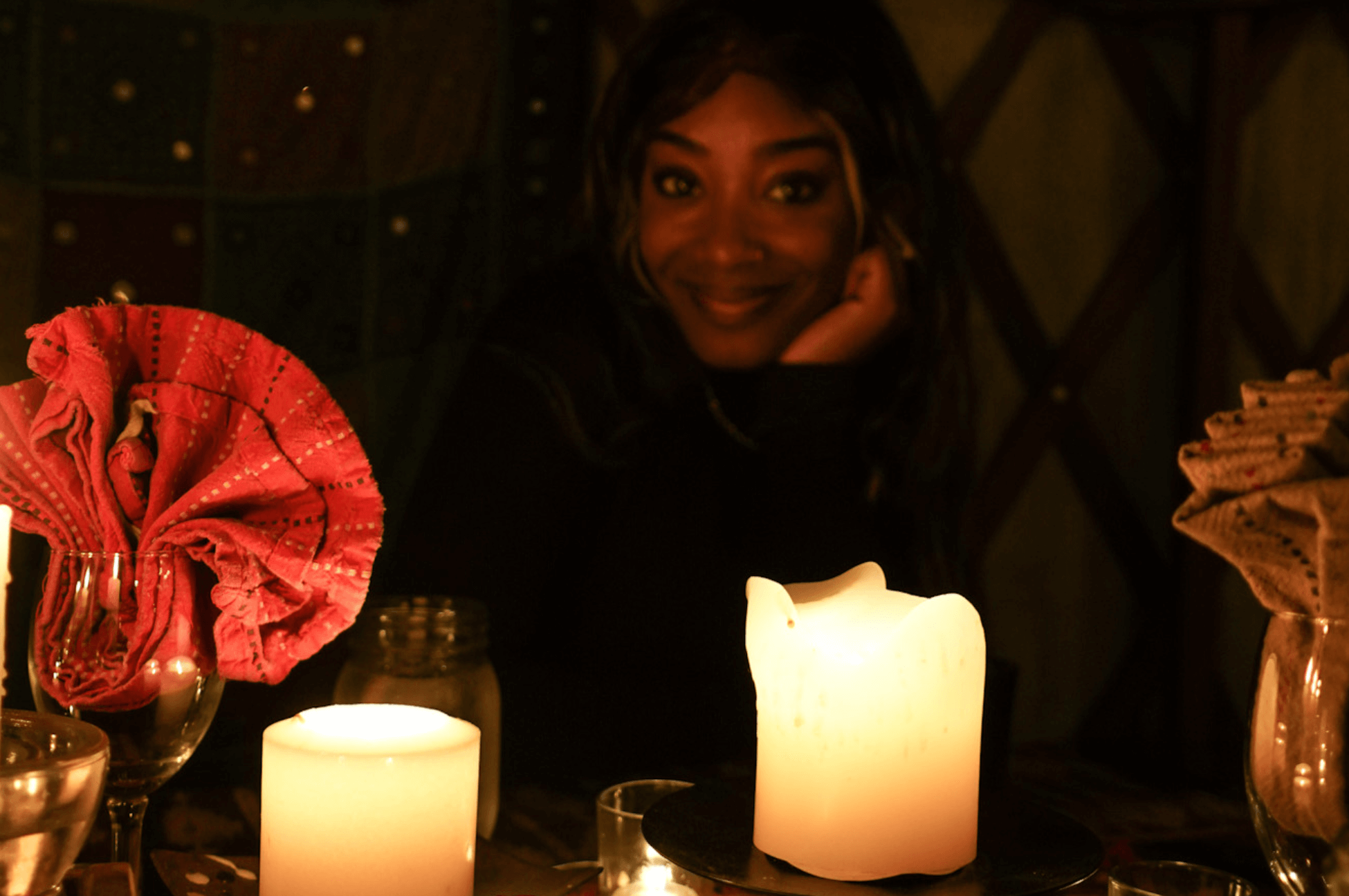 A black woman sits in the candle light at Blue Moon Yurt. 