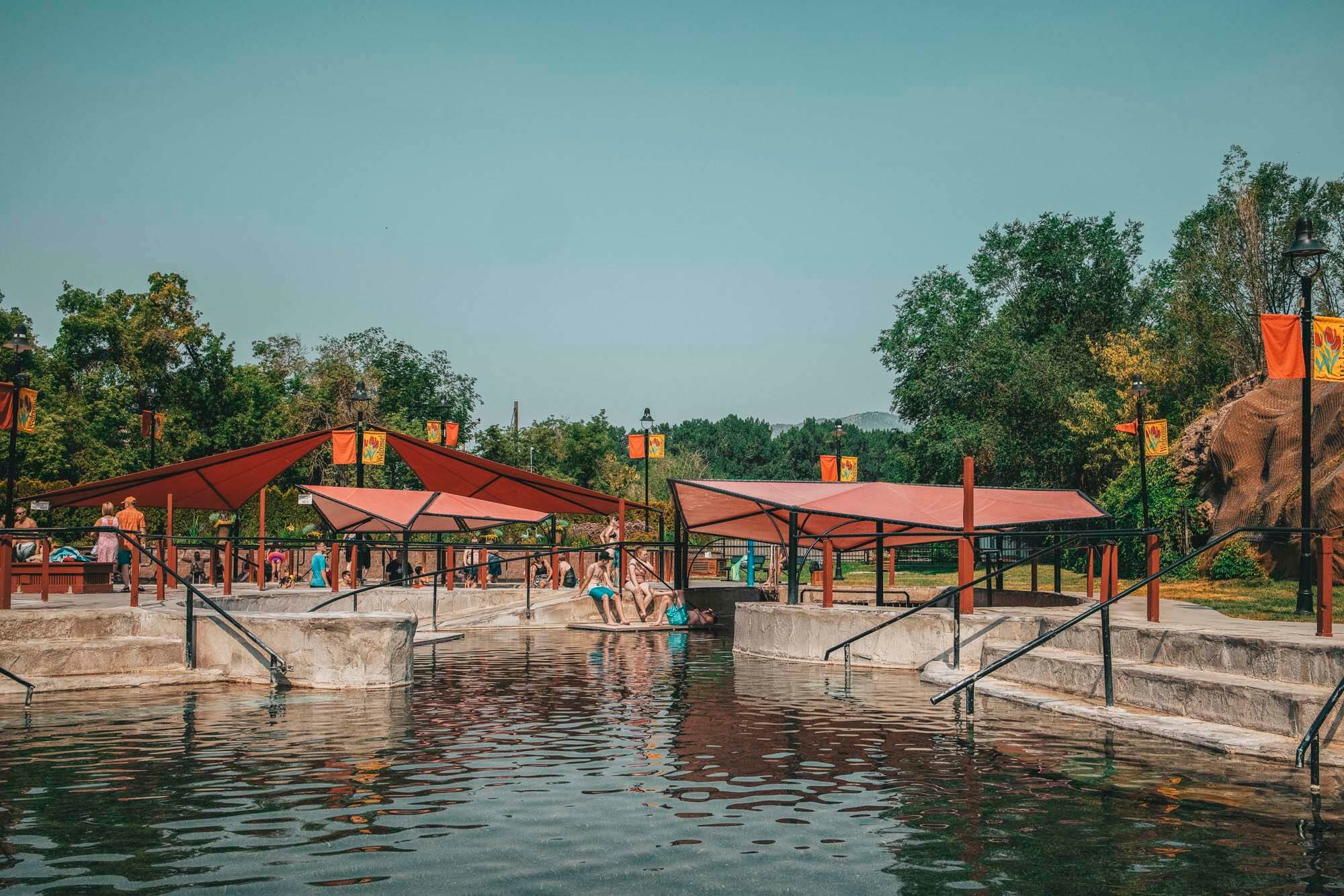 Several groups of people in bathing suits enjoying developed outdoor hot pools.