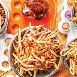 Plates of burgers and large bowls of fries on a table at Boise Fry Company.