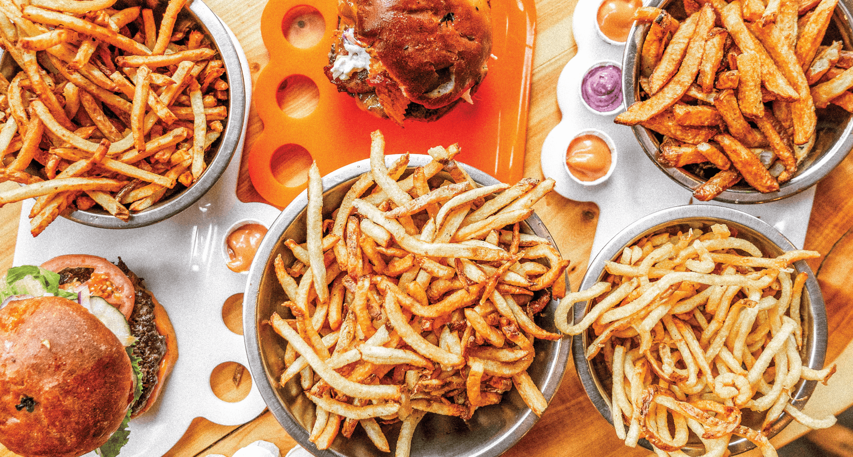 Plates of burgers and large bowls of fries on a table at Boise Fry Company.