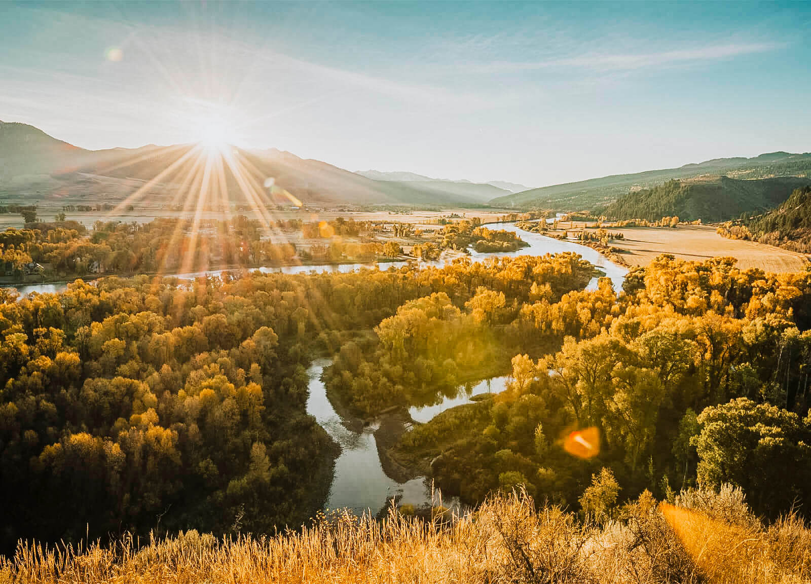 The sun shining across a landscape, golden across the South Fork of the Snake River in Idaho.