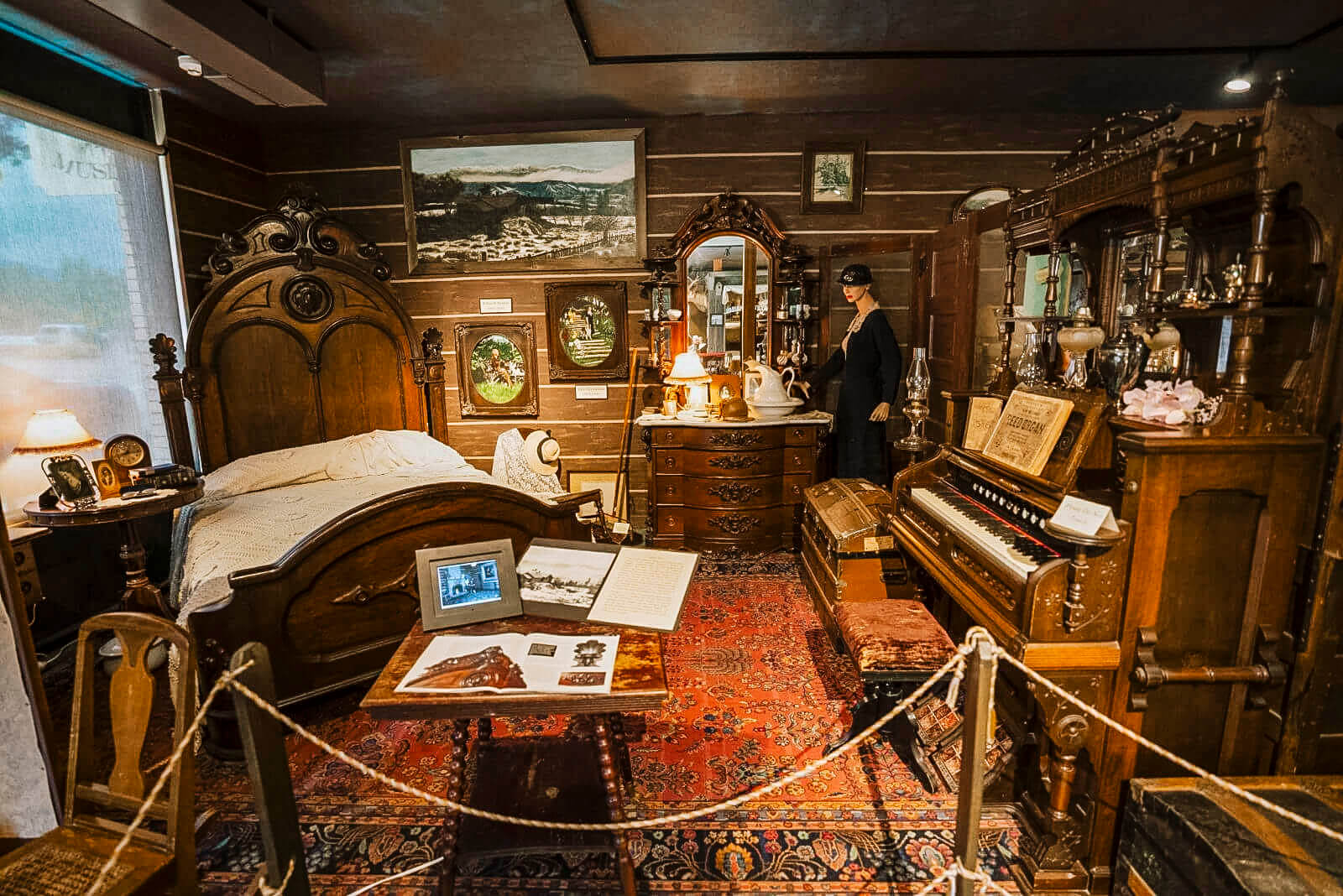 An exhibit of an old bedroom with antique, wooden furniture and a piano at the Boundary County Historical Museum.