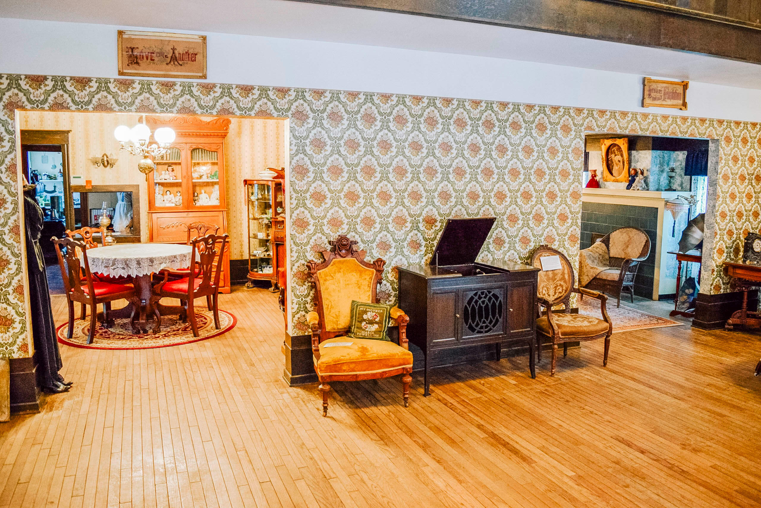 Two rooms containing antique tables, chairs and other furniture inside the Bingham County Historical Society Museum.