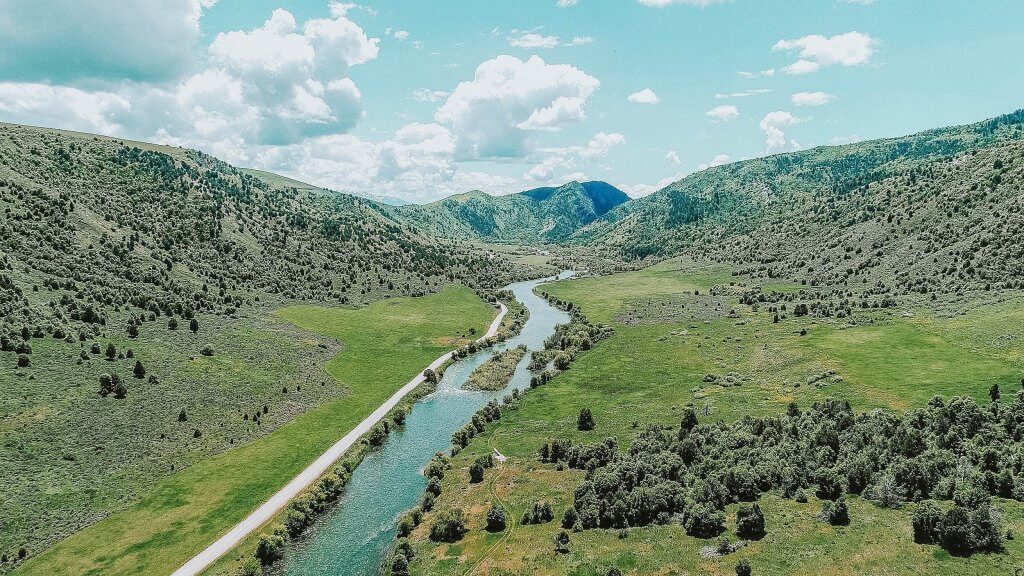 An aerial view of Oneida Narrows flowing through a green landscape with mountains in the distance.