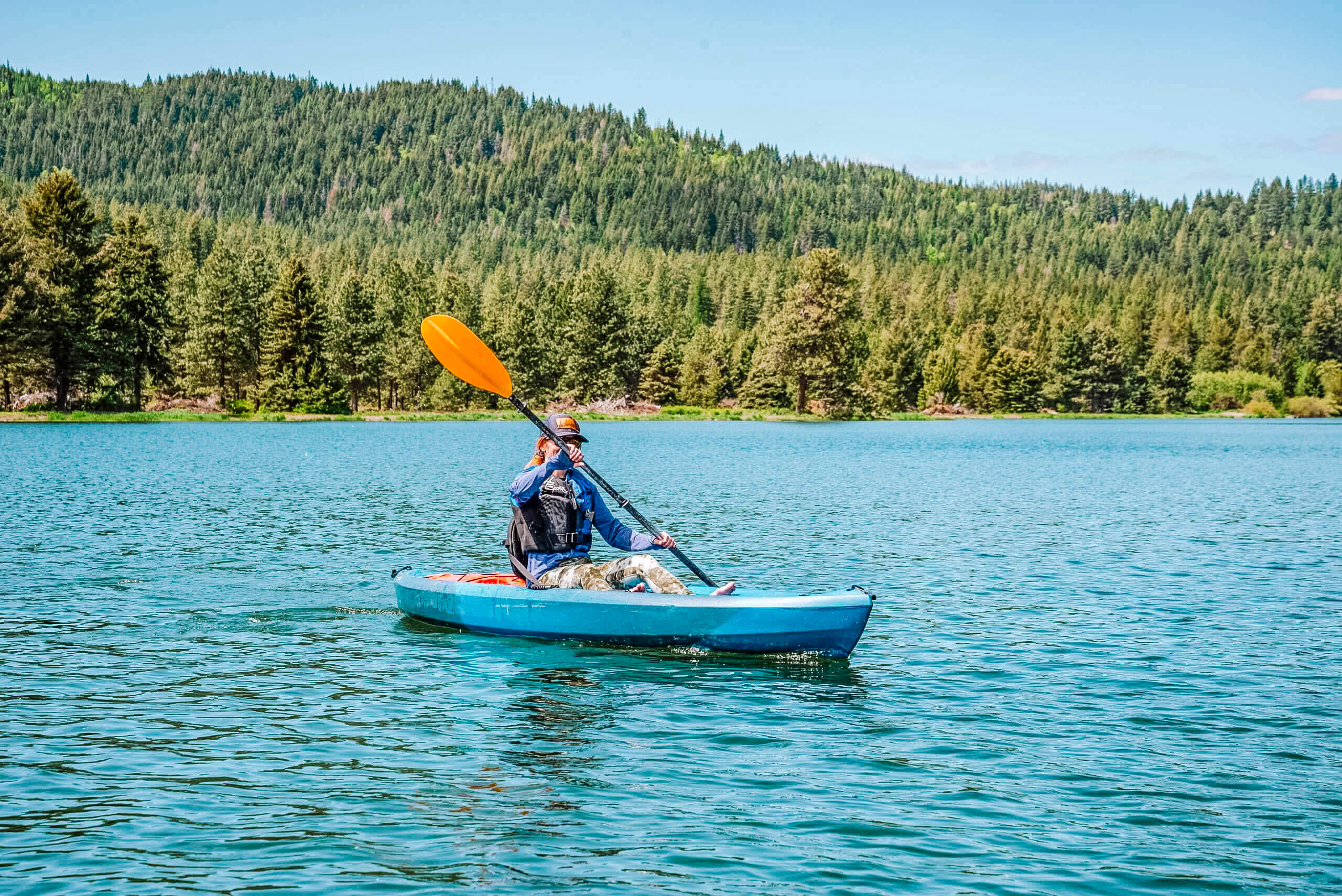 A person kayaking at Spirit Lake with tree-covered hills in the background.