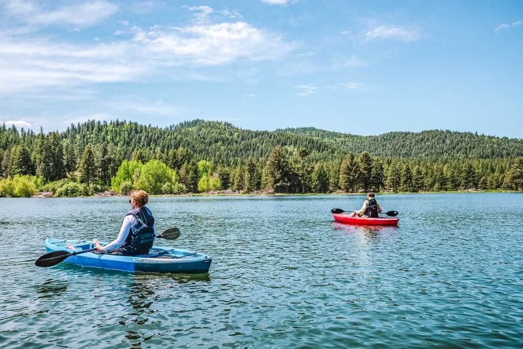 Two people kayaking at Spirit Lake, with tree-covered hills in the distance.