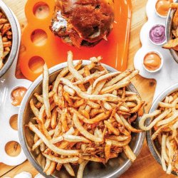 Plates of burgers and large bowls of fries on a table at Boise Fry Company.