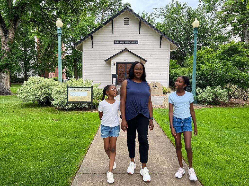 A woman and her daughters pose for a photo in front of the Idaho Black History Museum.