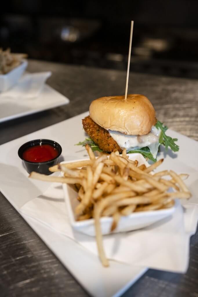 A sandwich, a dish of fries and cup of ketchup on a plate at Crafted Tap House + Kitchen.