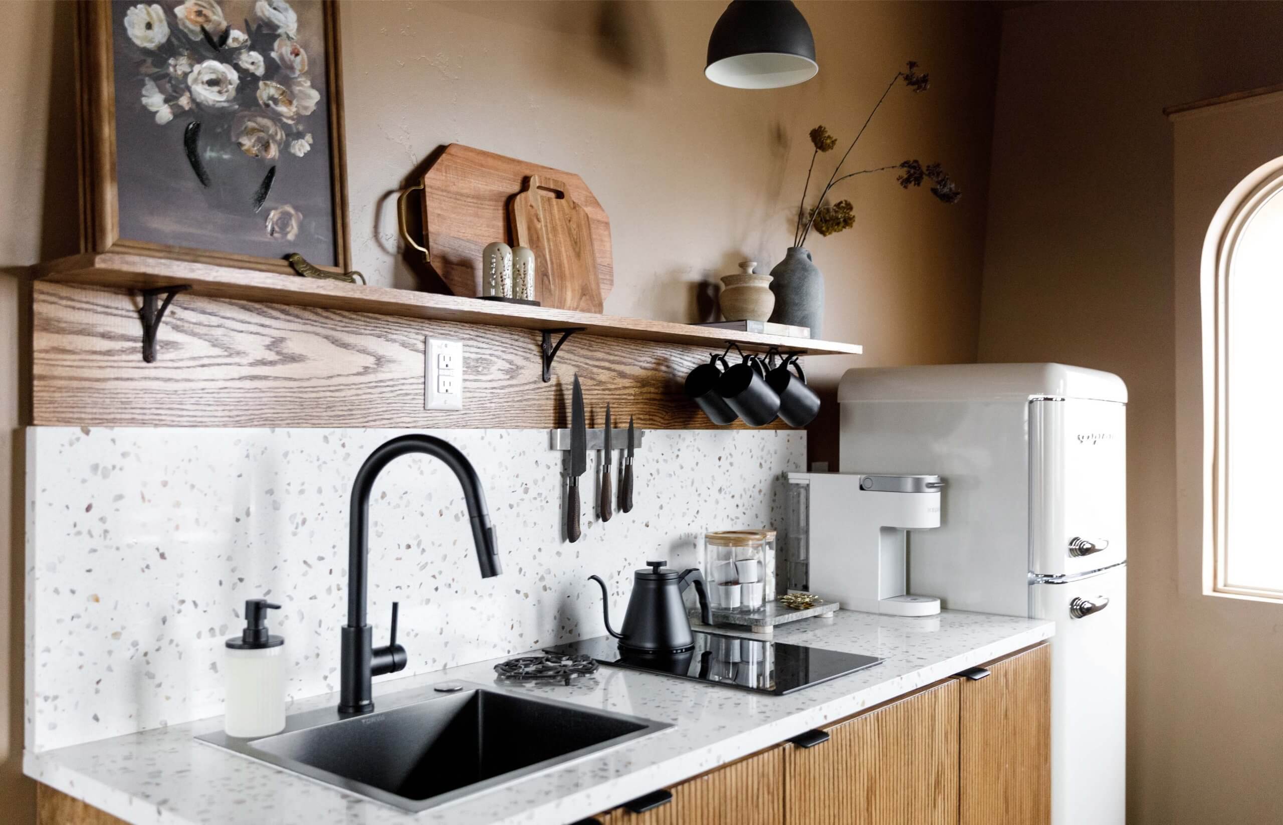 A close-up view of the kitchen inside The Flower Pot, where a beautiful white sink sits beneath a framed photo of flowers and a fresh bouquet.