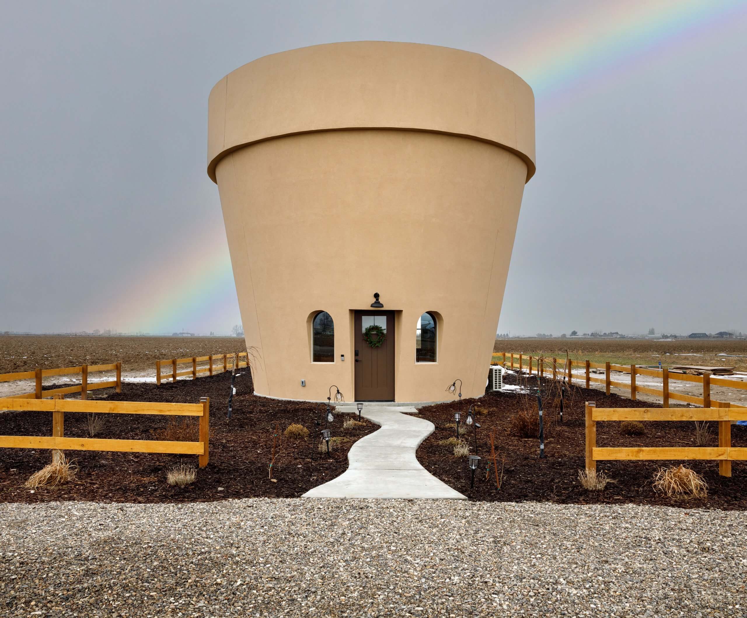 A rainbow stretches over the sky above the Flower Pot, life-sized flower pot Airbnb in Burley, Idaho.