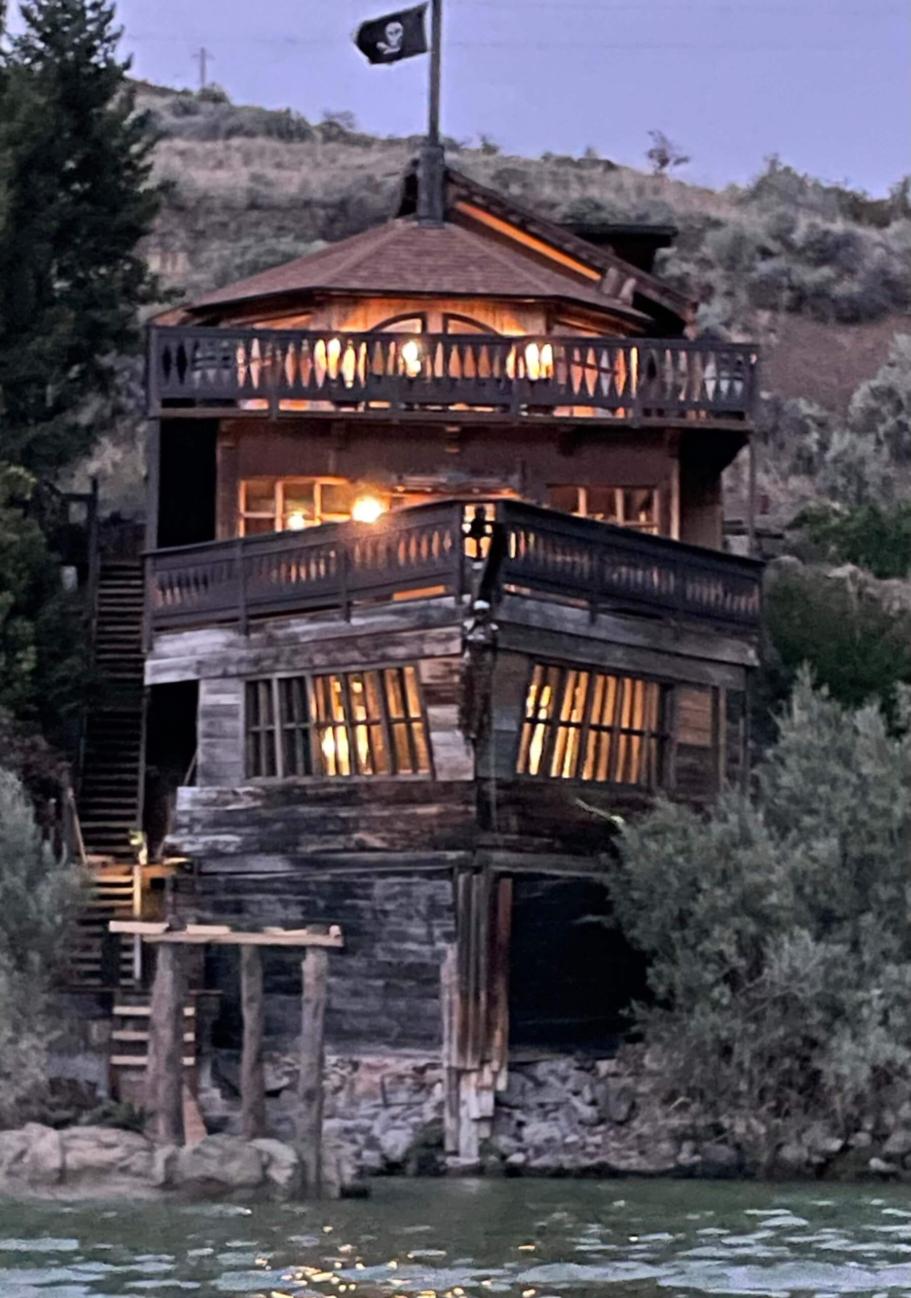 The three-storied Shipwreck House stands with lights glowing as the house looks like it's been shipwrecked on the land in Salmon, Idaho.