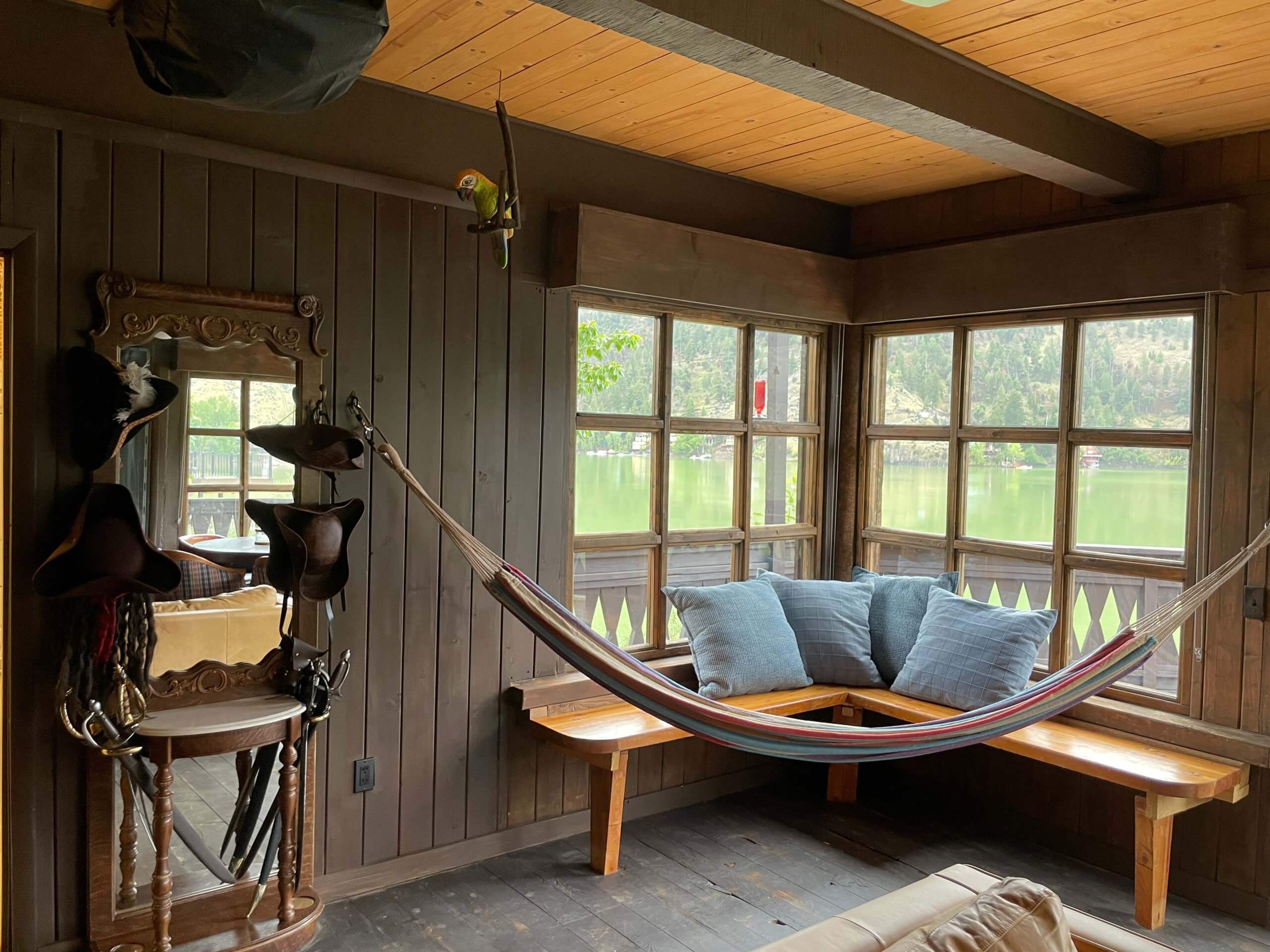 A multi-colored hammock hangs by the blue pillows propped against a pane of windows inside the Shipwreck House in Salmon, Idaho.