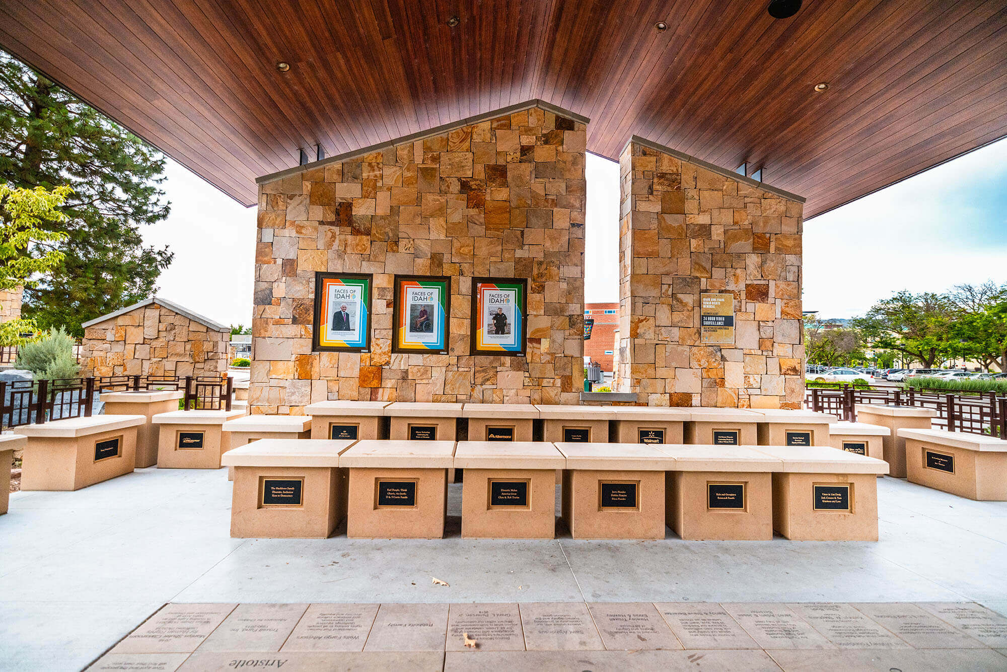 A series of stone monuments with name plates and and posters on a wall inside a building at the Idaho Anne Frank Human Rights Memorial.