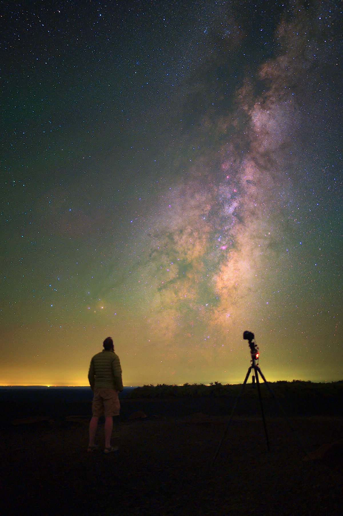 A man stands with a tripod admiring the night sky.