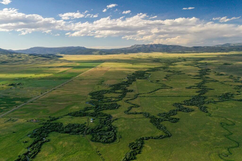 An aerial view of a sprawling green landscape and mountains in the distance.