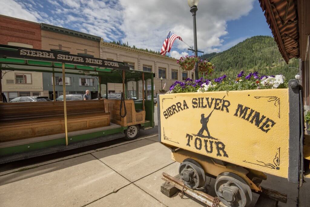 A sign that reads Sierra Silver Mine Tour beside a tour trolley with the same signage.