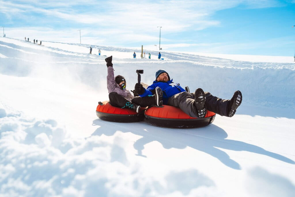 Two family members enjoying snow tubing.