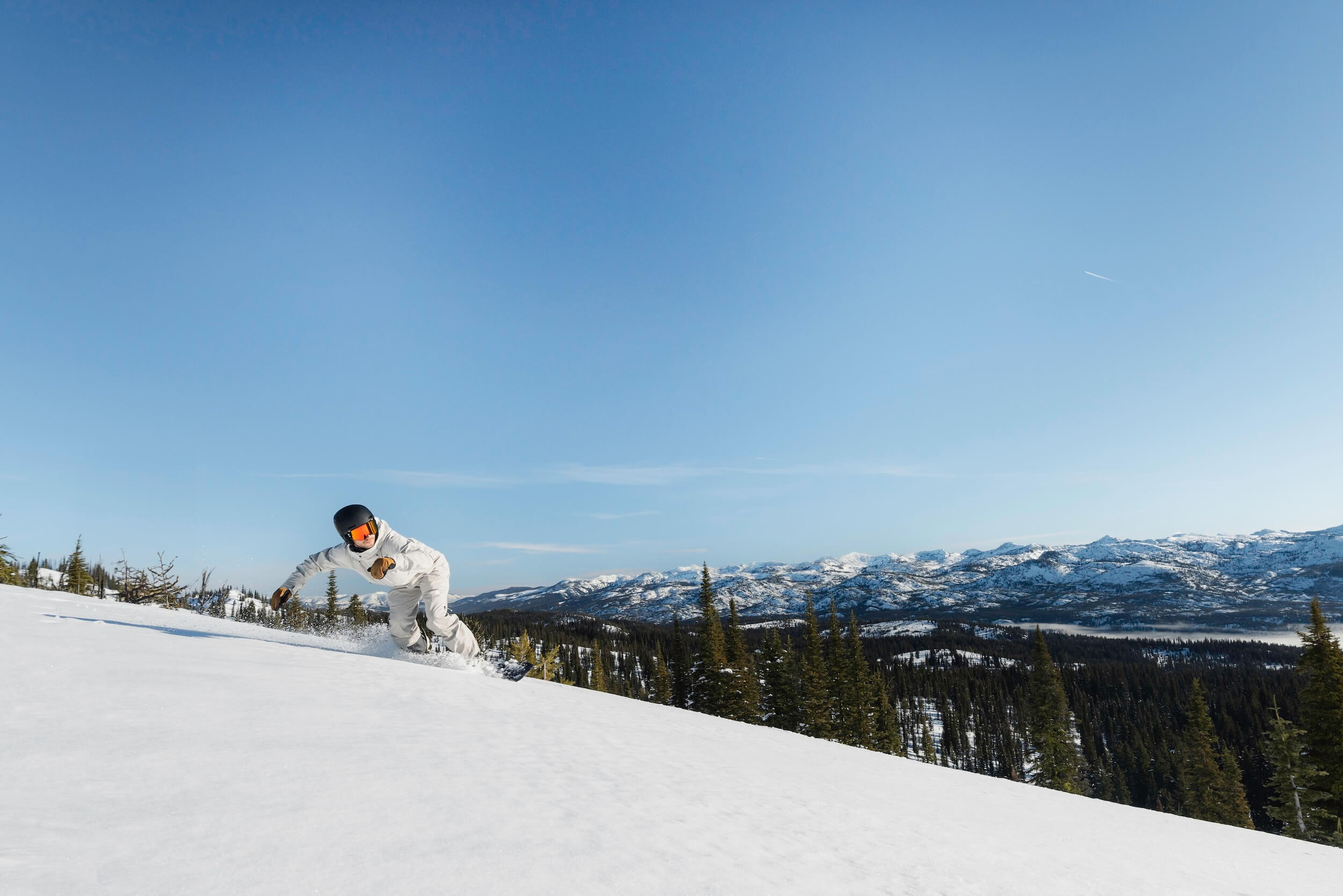 Snowboarder carving through fresh snow on a scenic trail at Brundage Mountain Resort in Idaho.