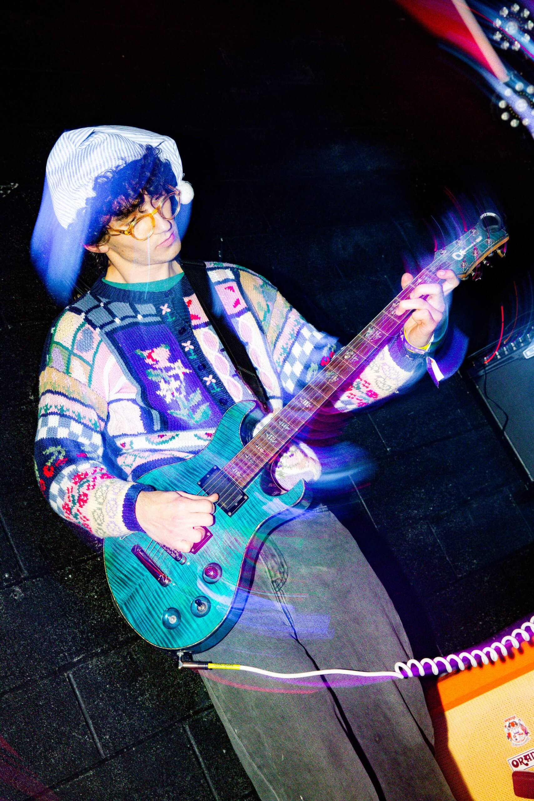 A man in a sweater and hat plays a guitar at Treefort Music Fest.