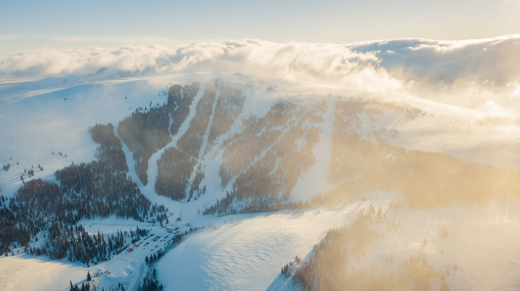 An aerial view overlooking the clouds rolling above the snowy Pomerelle Mountain Resort.