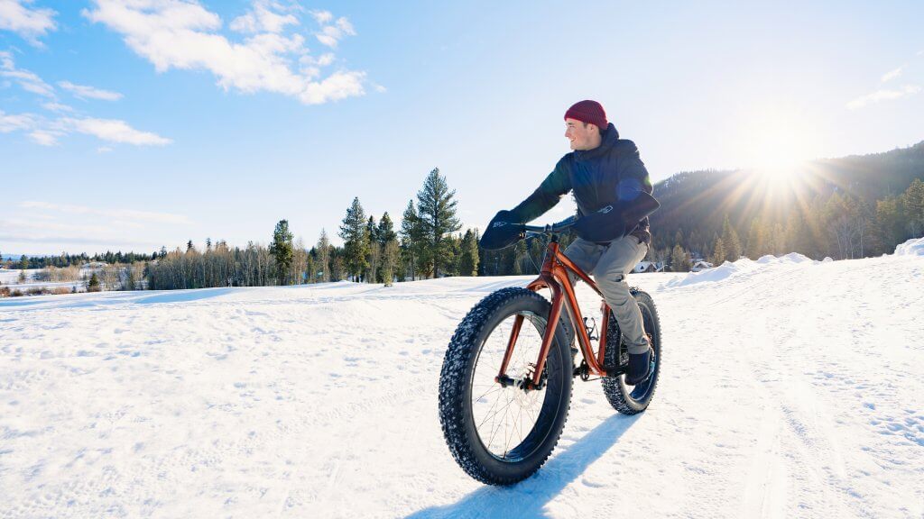 A person riding a fat bike across a sprawling field of snowy terrain at Tamarack Resort.