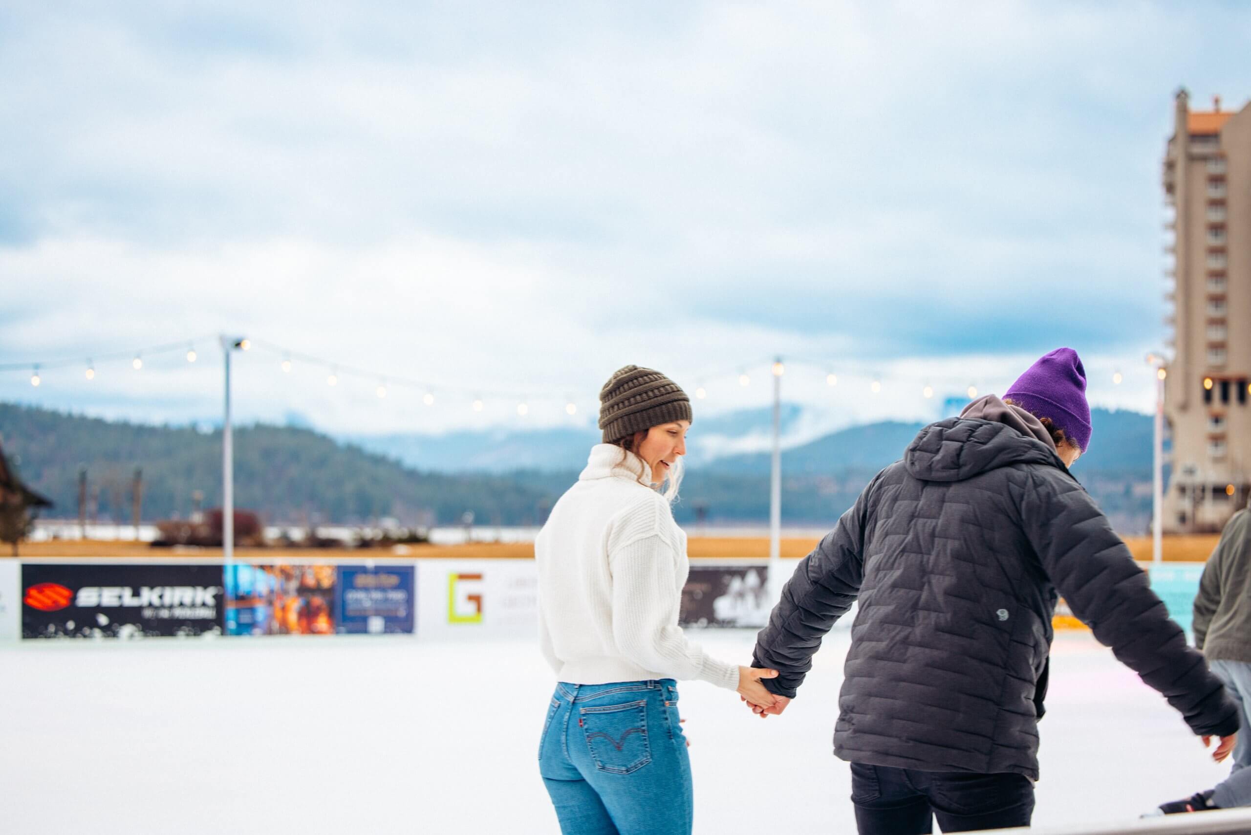 An image of two people holding hands while ice skating.