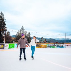 Two people holding hands and skating on the rink at the rink at CDA on Ice.