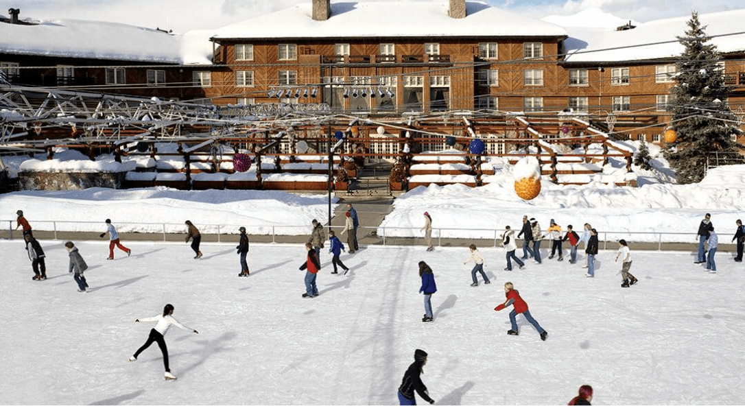 Several people skating at the Sun Valley Outdoor Ice Rink in front of Sun Valley Lodge.