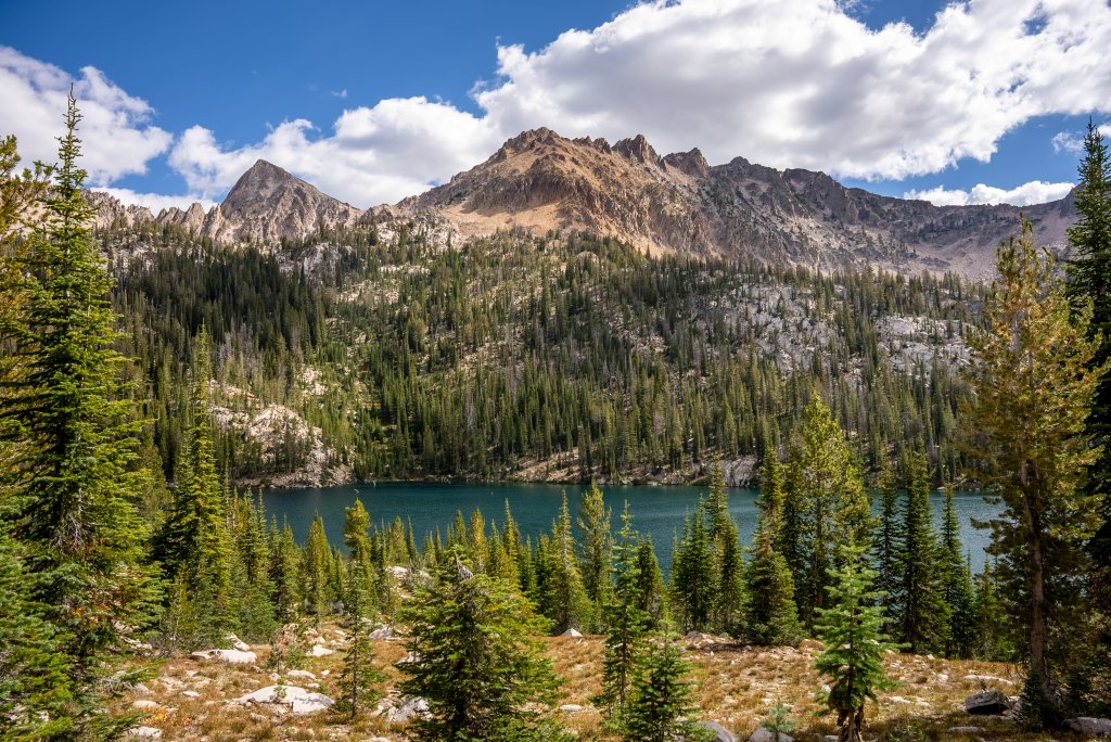 A view of Hidden Lake surrounded by forests and rugged mountain peaks.