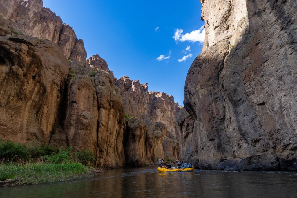 Rafters paddling a yellow raft through the narrow rock canyons of the Bruneau River