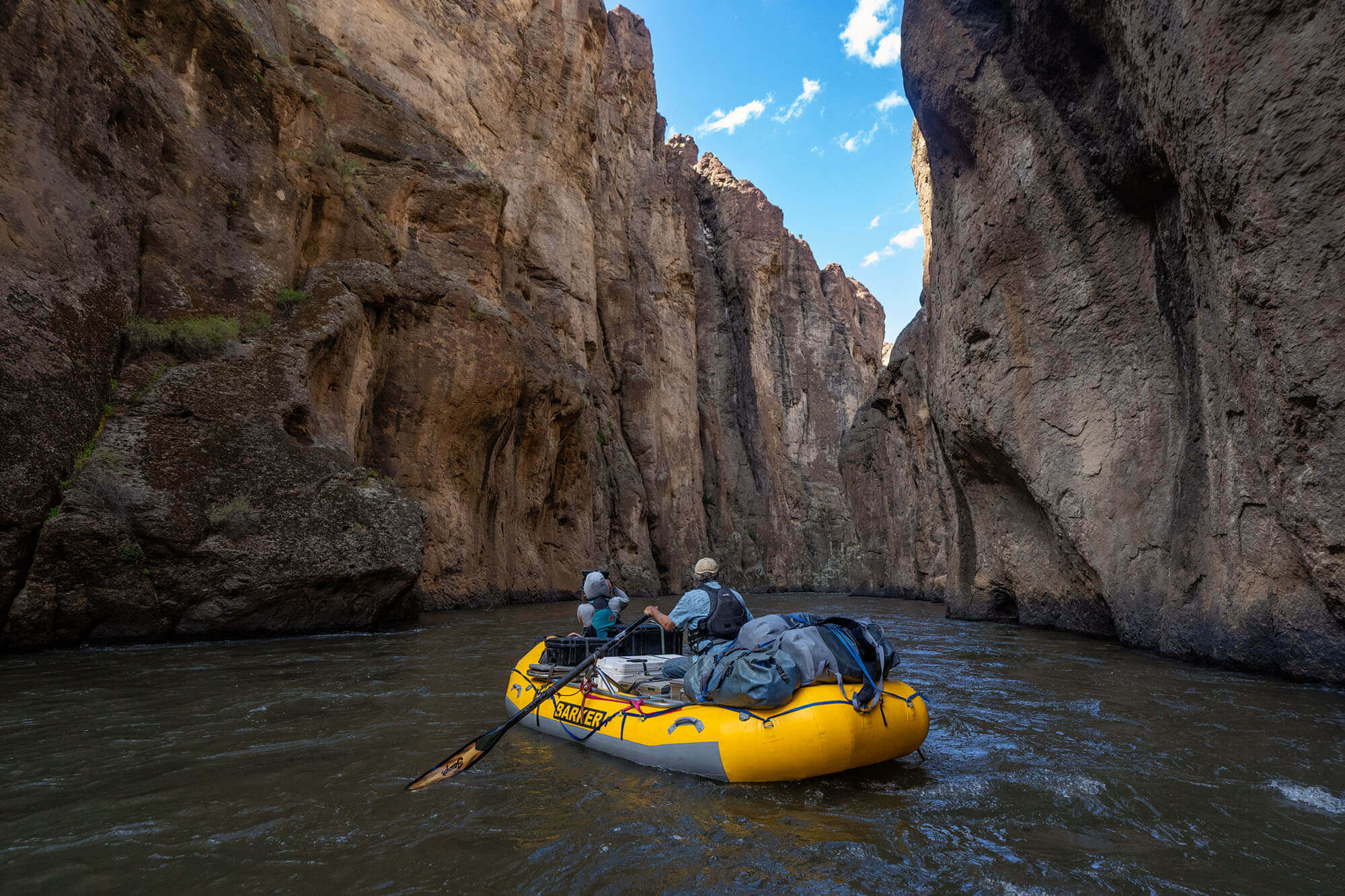 Two adventurers go whitewater rafting on the Bruneau River with Barker River Expeditions, canyon cliffs rising tall.