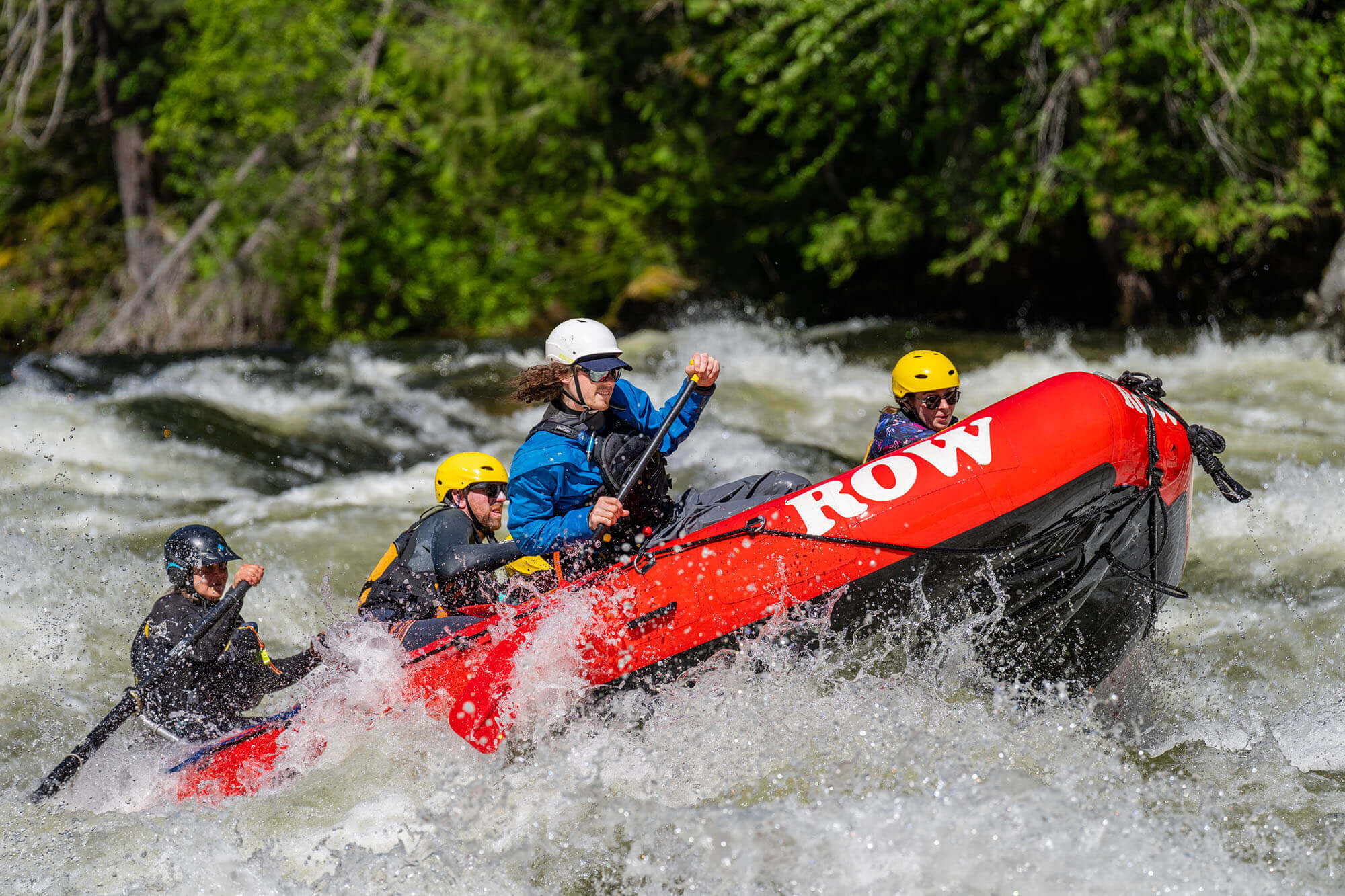 Rapids surge on the St. Joe River, tall lush trees lining the crash of the waves.