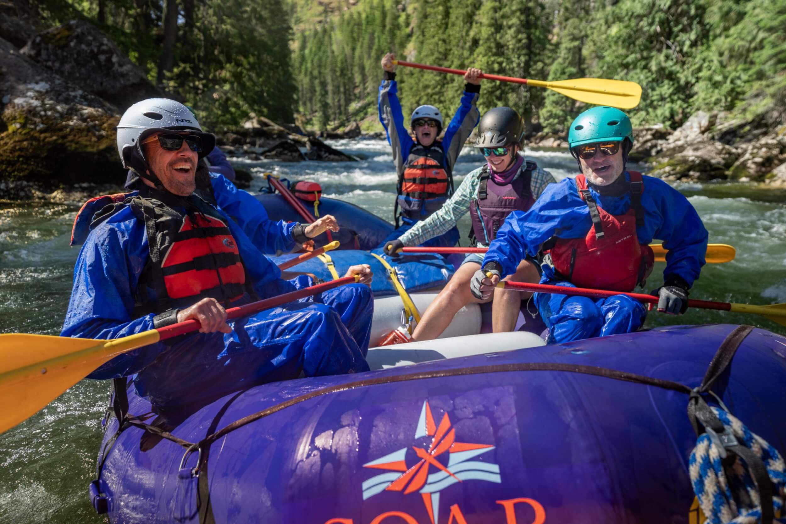Group of whitewater rafters paddling the Selway River with SOAR Northwest, smiling and celebrating in calm water.