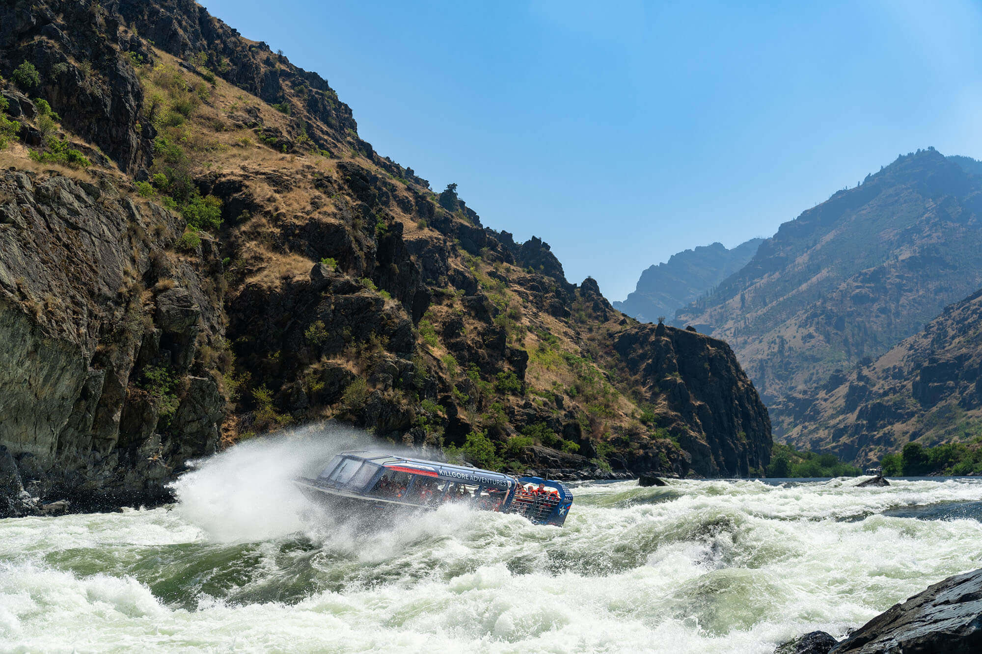 A group goes jet boating on the Snake River near Hells Canyon with Killgore Adventures, water splashing in an action shot.