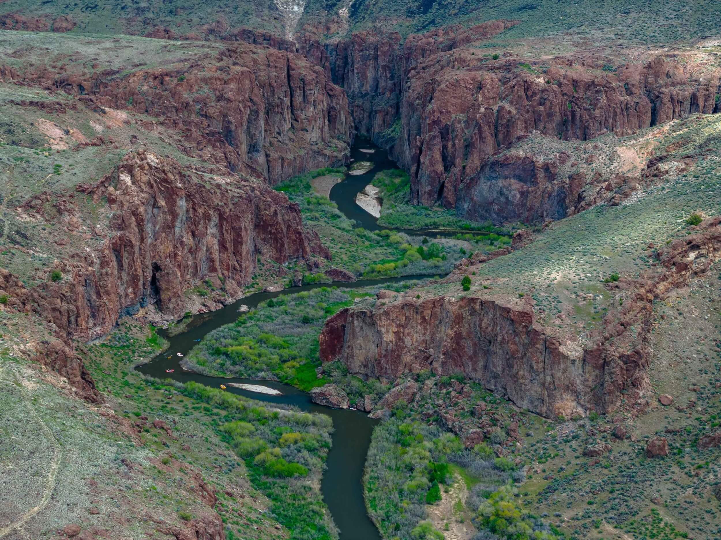 Aerial view of rafts floating through a dramatic red-rock canyon on the Bruneau River.