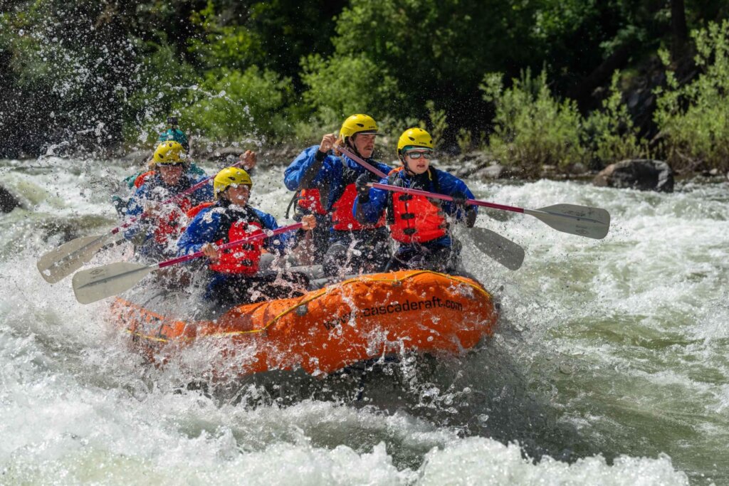 Close-up of rafters paddling through a rapid with water splashing into the boat on the Payette River.