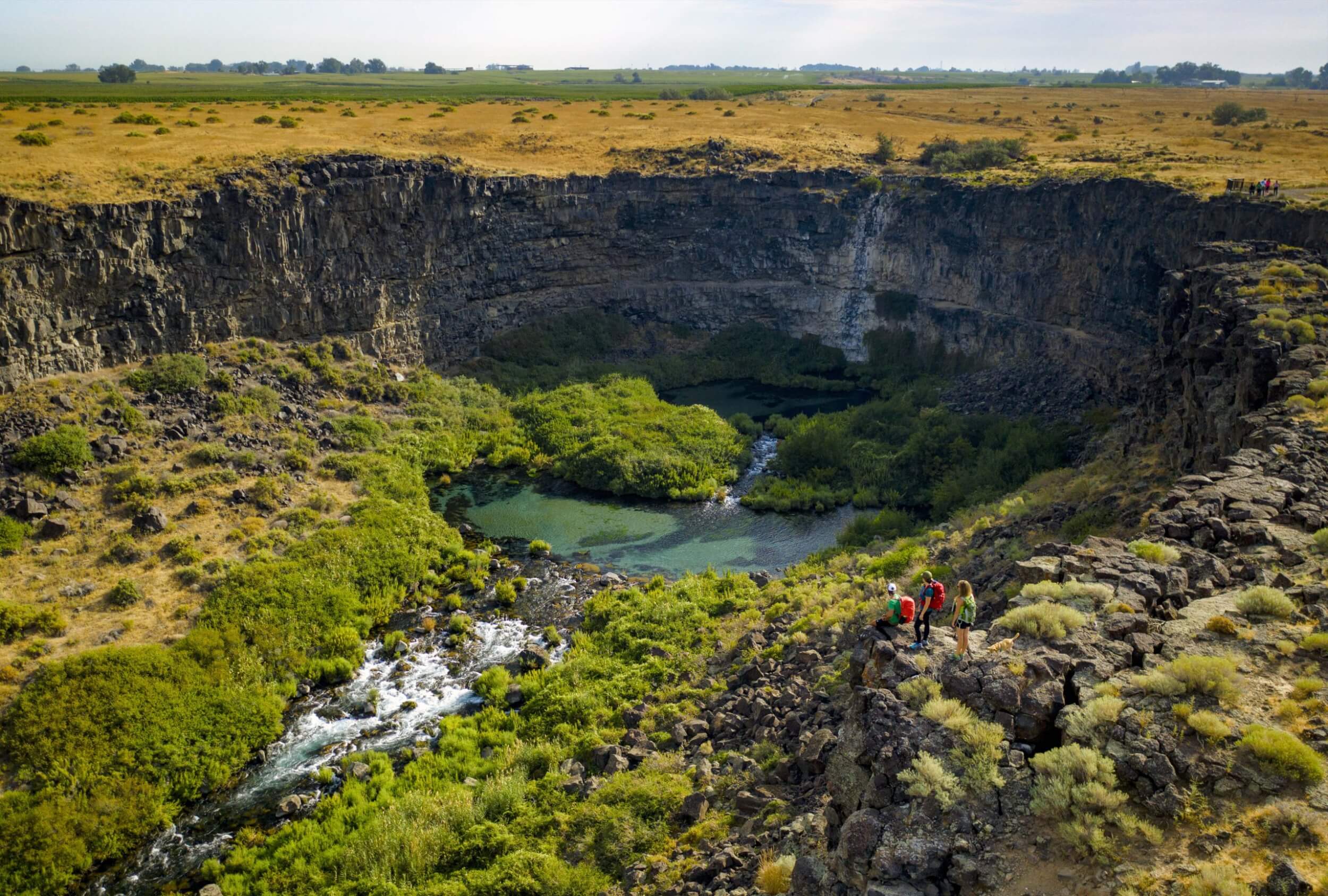 Try These 7 Scenic Byways to Find Natural Wonders Three people standing on a cliff overlooking Earl M. Hardy Box Canyon Springs Nature Preserve.
