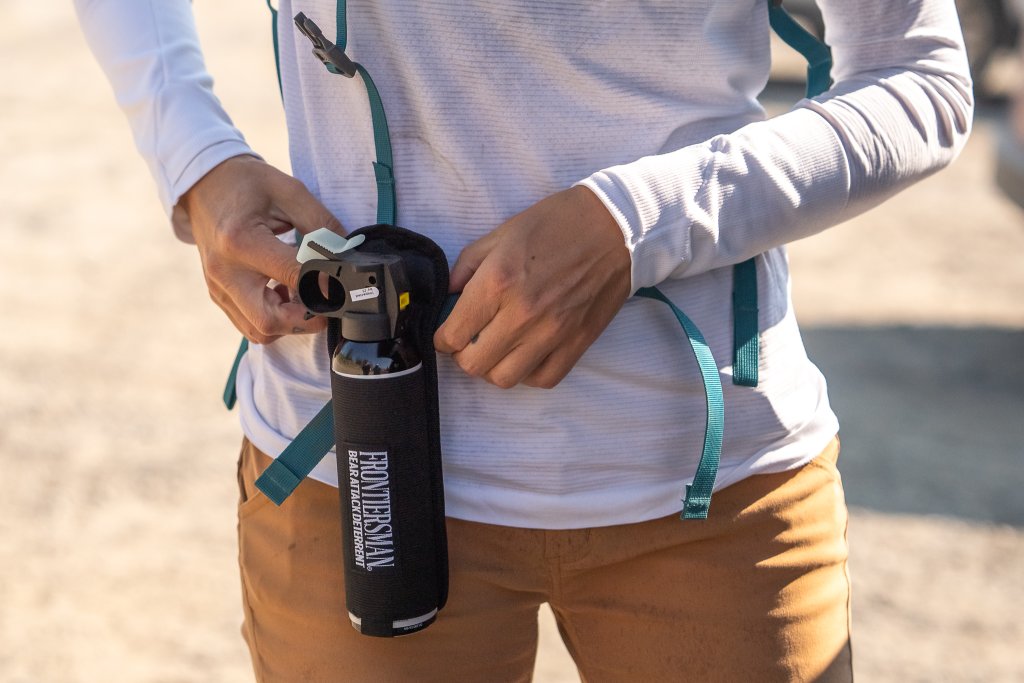 Travel With Care: Safety in Bear Country A hiker straps bear spray to their waist.