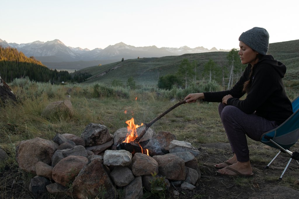 TRAVEL WITH CARE: CAMPING WITH CARE A camper tends to a campfire.
