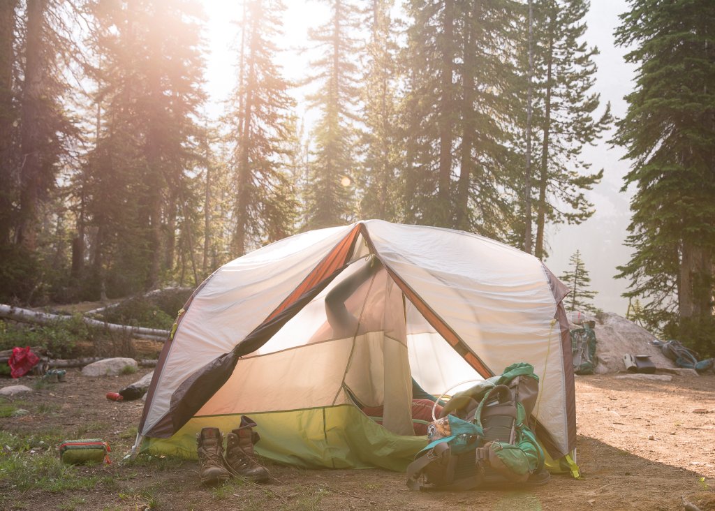 TRAVEL WITH CARE: CAMPING WITH CARE A person unzips their tent at a dispersed campsite.