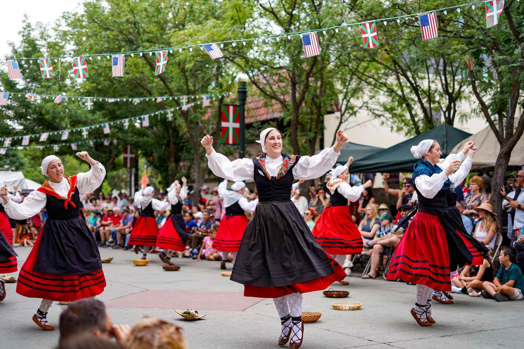A group of Basque dancers performing in front of a crowd of people.