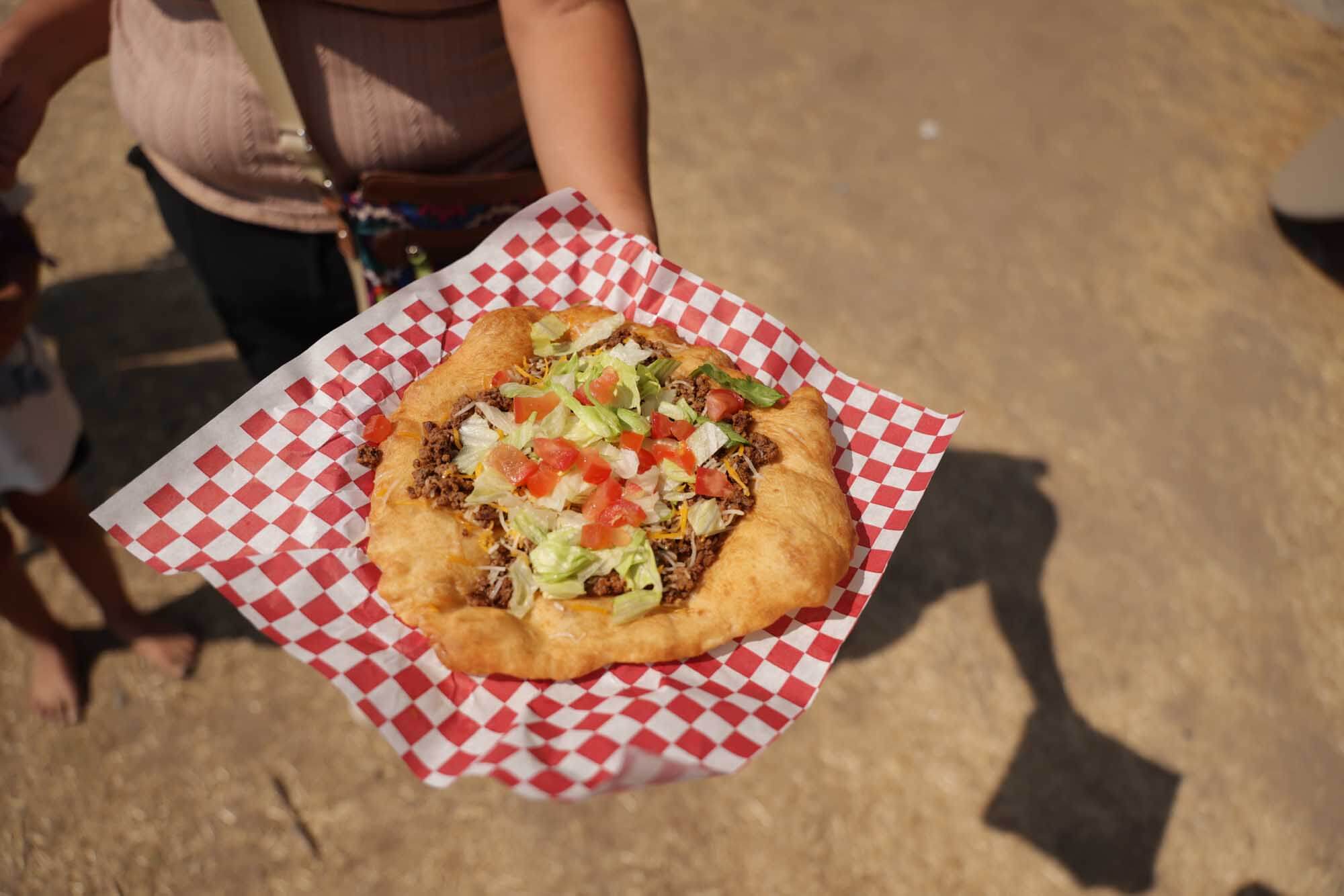 A person holds Indian fry bread on a red, checkered paper at the Shoshone-Bannock Indian Festival in Fort  Hall.
